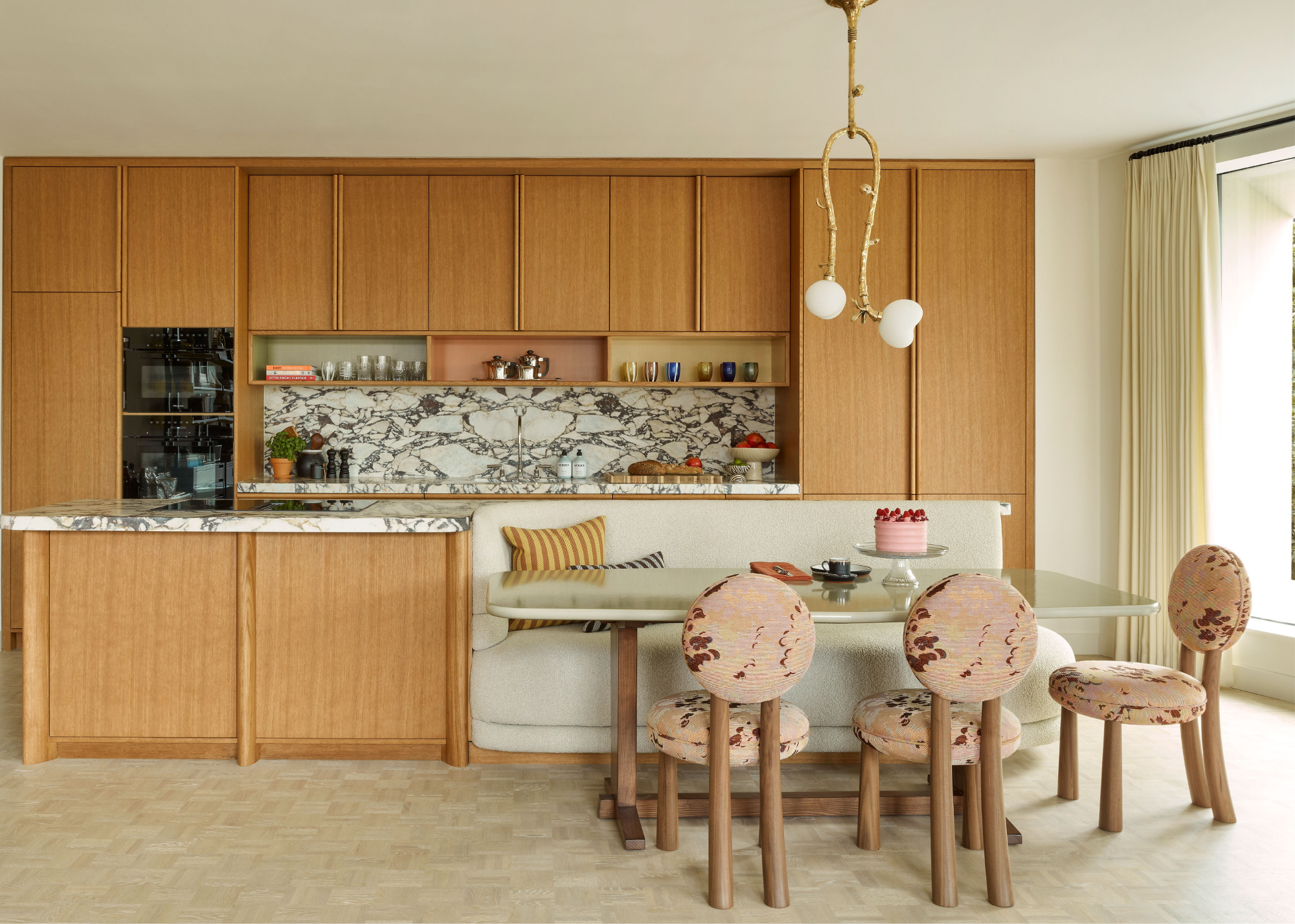 open plan kitchen with wooden cabinetry, calcutta viola surfaces, and banquet seating built into the wooden island