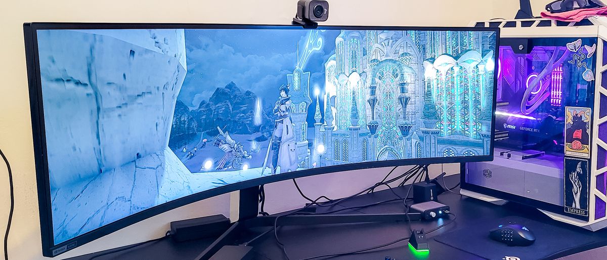 Samsung Odyssey Neo G9 on a desk next to a gaming pc with accessories