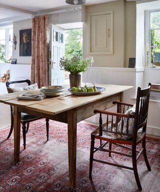 country dining room with farmhouse table, tongue and groove, antique rug on floor and door open leading outdoors