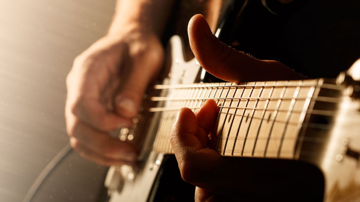 Hands of man playing electric guitar using the bend technique