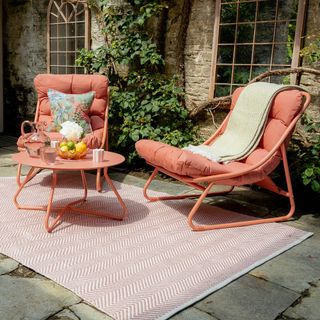 Pink seating area with loungers, coffee table and rug in Anouska Lancaster's walled garden outdoor kitchen area