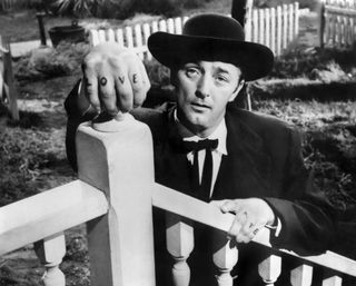 Robert Mitchum with love tattooed on his knuckles leans over a stair railing in The night of the hunter