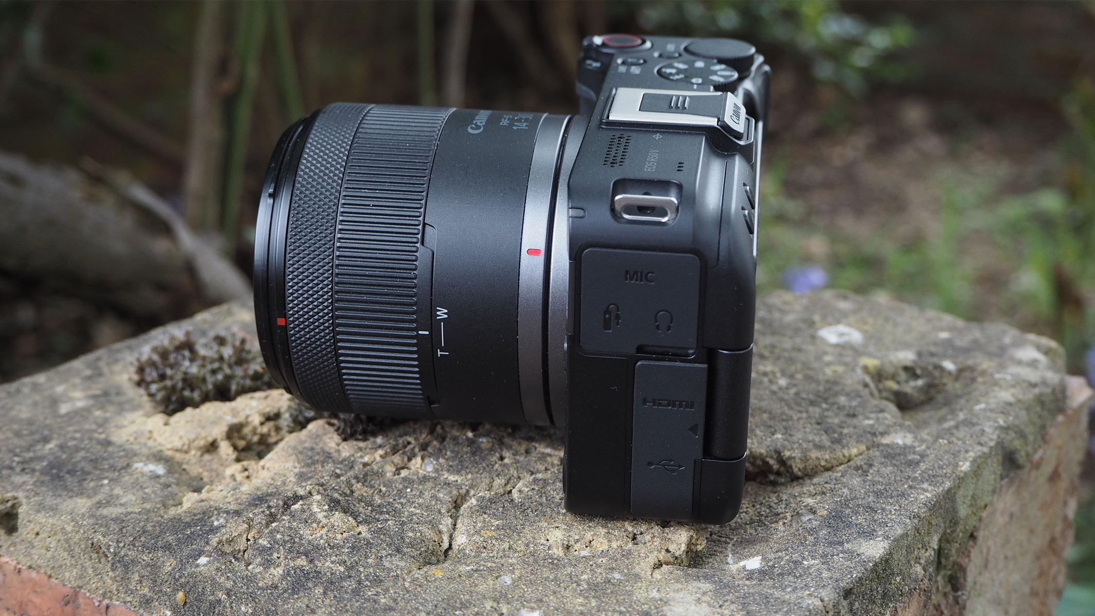 Side view of the Canon EOS R50 V on a stone wall.