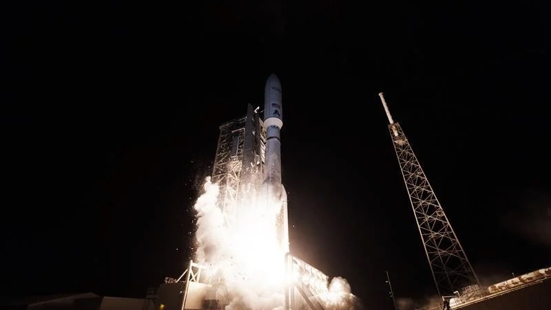 a large white rocket launches into a dark night sky