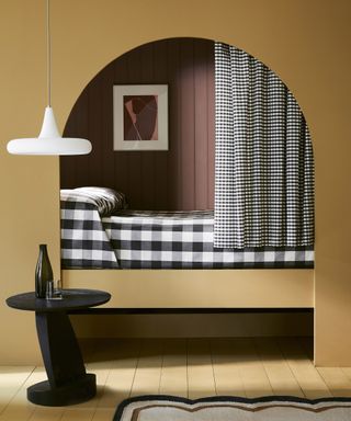 Yellow alcove bedroom design with black table, white ceiling lamp and gingham bedding by Little Greene Paint Company