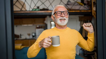 Mature man enjoys morning coffee at the door to his terrace