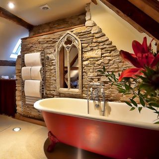 bath area with stone texture wall and bathtub