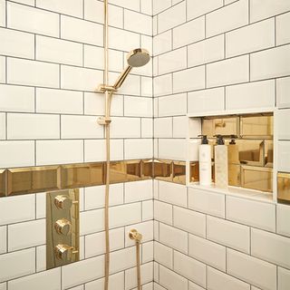shower storage ideas with gold tiles and shower fittings