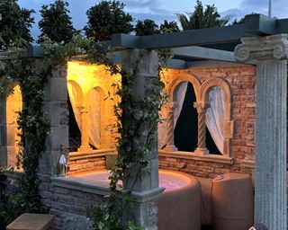 hot tub underneath a stone and timber pergola at night