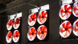 Red cooling fans spin in a data centre wall