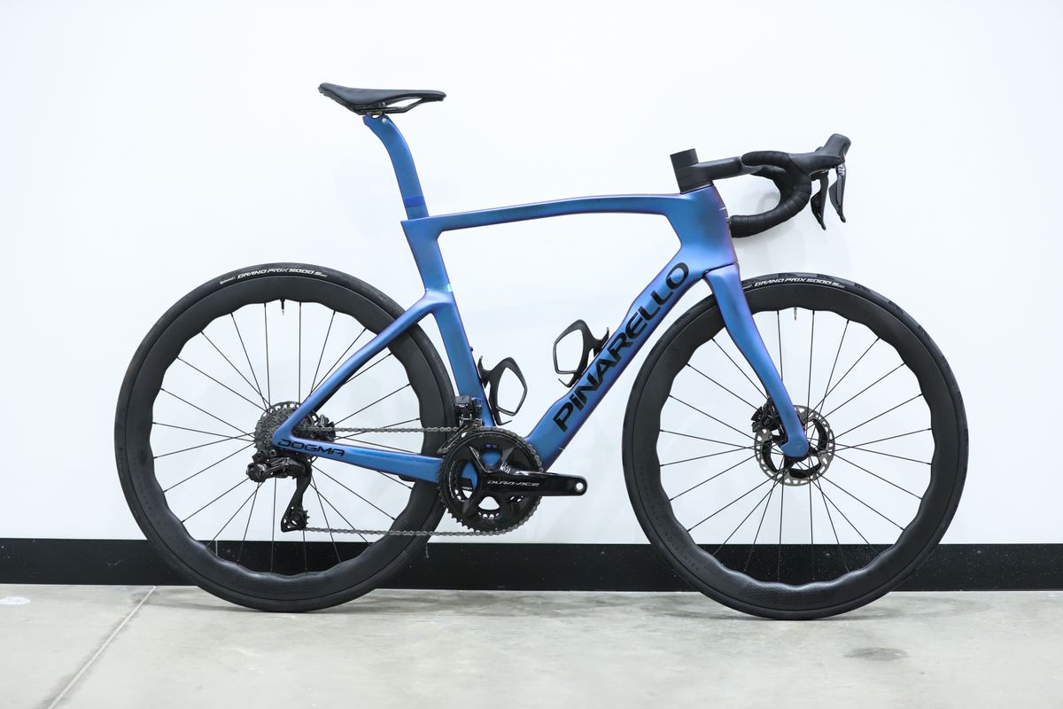 A blue pinarello dogma f stands against a white wall