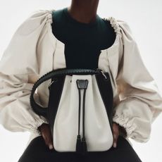 a model holds a black-and-white bucket bag