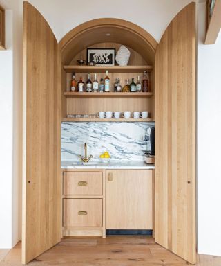 Arched coffee bar with wooden doors, wooden joinery, cabinets and a marble splashback