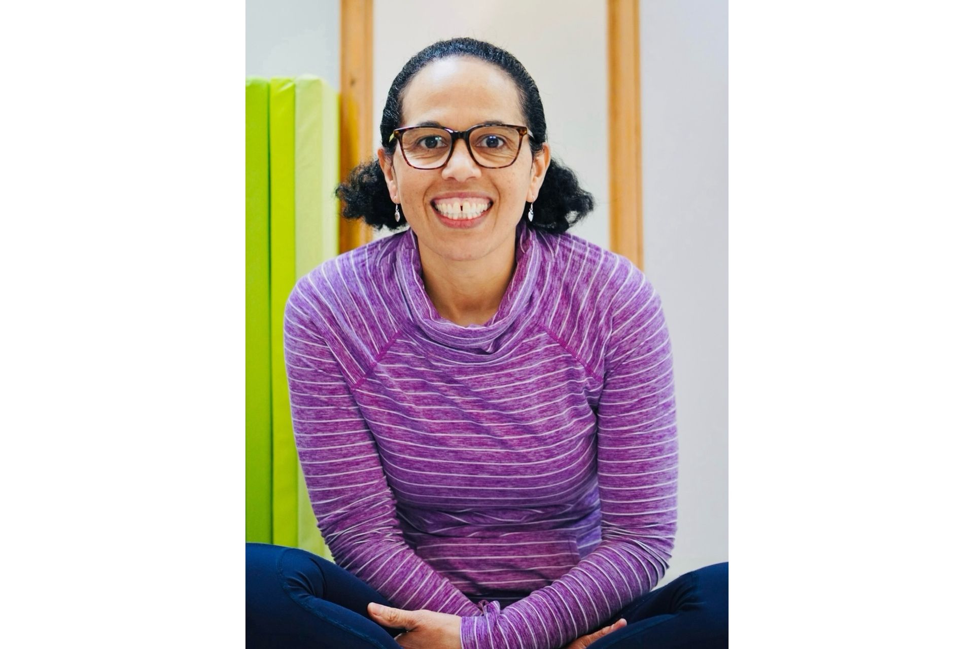 Amanda Daley sits crossed legged smiling with a purple top on