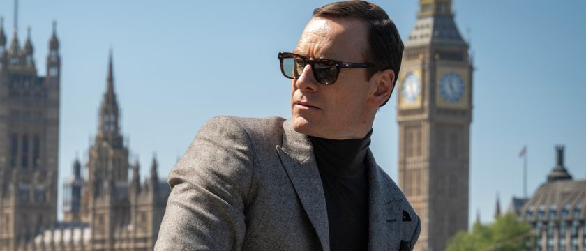 Michael Fassbender leans in front of the London skyline while wearing sunglasses and a suit in Black Bag.