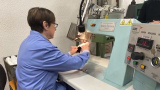 Worker using industrial sewing machine to stitch hiking boot uppers together