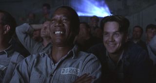 Morgan Freeman and Tim Robbins smile while watching a movie in The Shawshank Redemption.