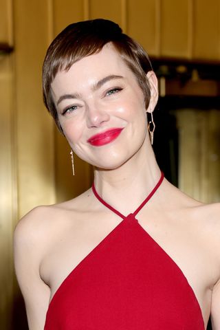 Emma Stone is pictured with a short pixie cut and wearing a red dress at SNL50: The Anniversary Special on February 16, 2025 in New York City.