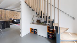 white hallway with colourful show storage under stairs