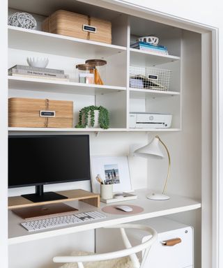 White desk with computer and lamp in closet
