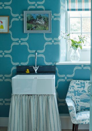 downstairs cloakroom in converted cow byre home with blue wallpaper and Vanessa Arbuthnott fabrics
