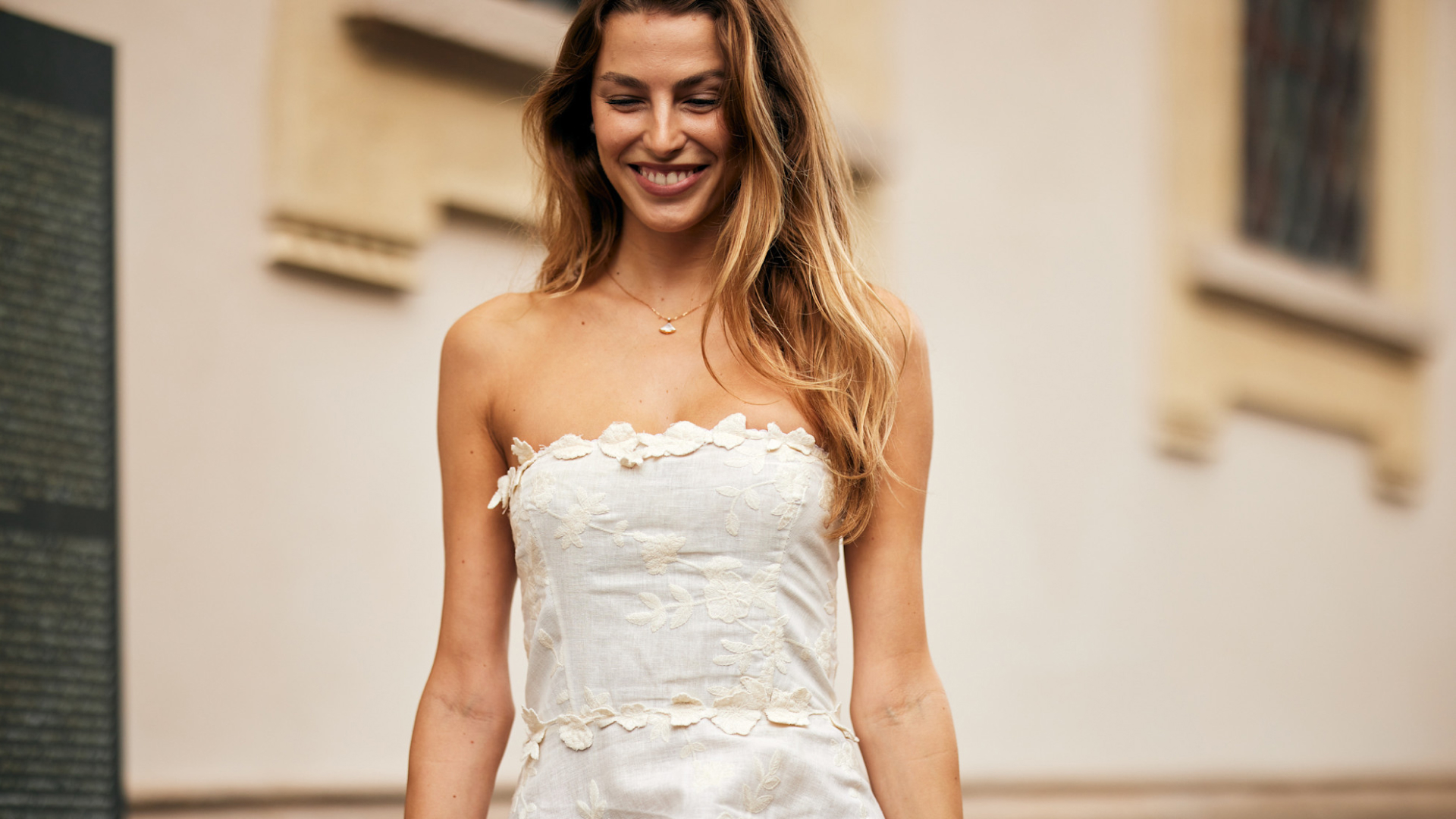 blonde fashion week attendee smiling wearing strapless white dress