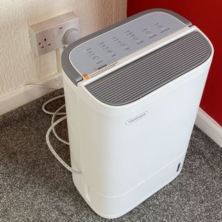 Vonhaus dehumidifier plugged in next to red wall