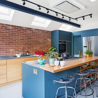 kitchen with blue and wooden cabinets and exposed brick wall