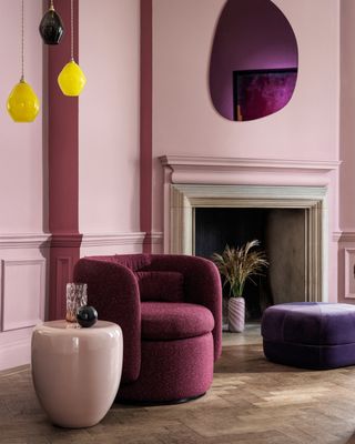Cross Stitch pink paint color on living room rooms with pink velvet furniture drop pendant light and oval-shaped mirror above fireplace
