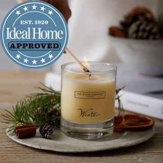 The Ideal Home approved White Company Winter Signature Candle being lit with a match
