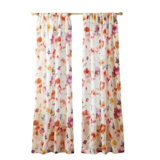 Two white curtain panels with colorful flowers on a gold rod