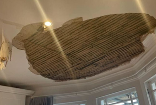A picture of a hole in a ceiling with lath work showing