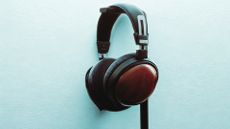 FiiO FT13 closed back headphones hanging on a blue wall