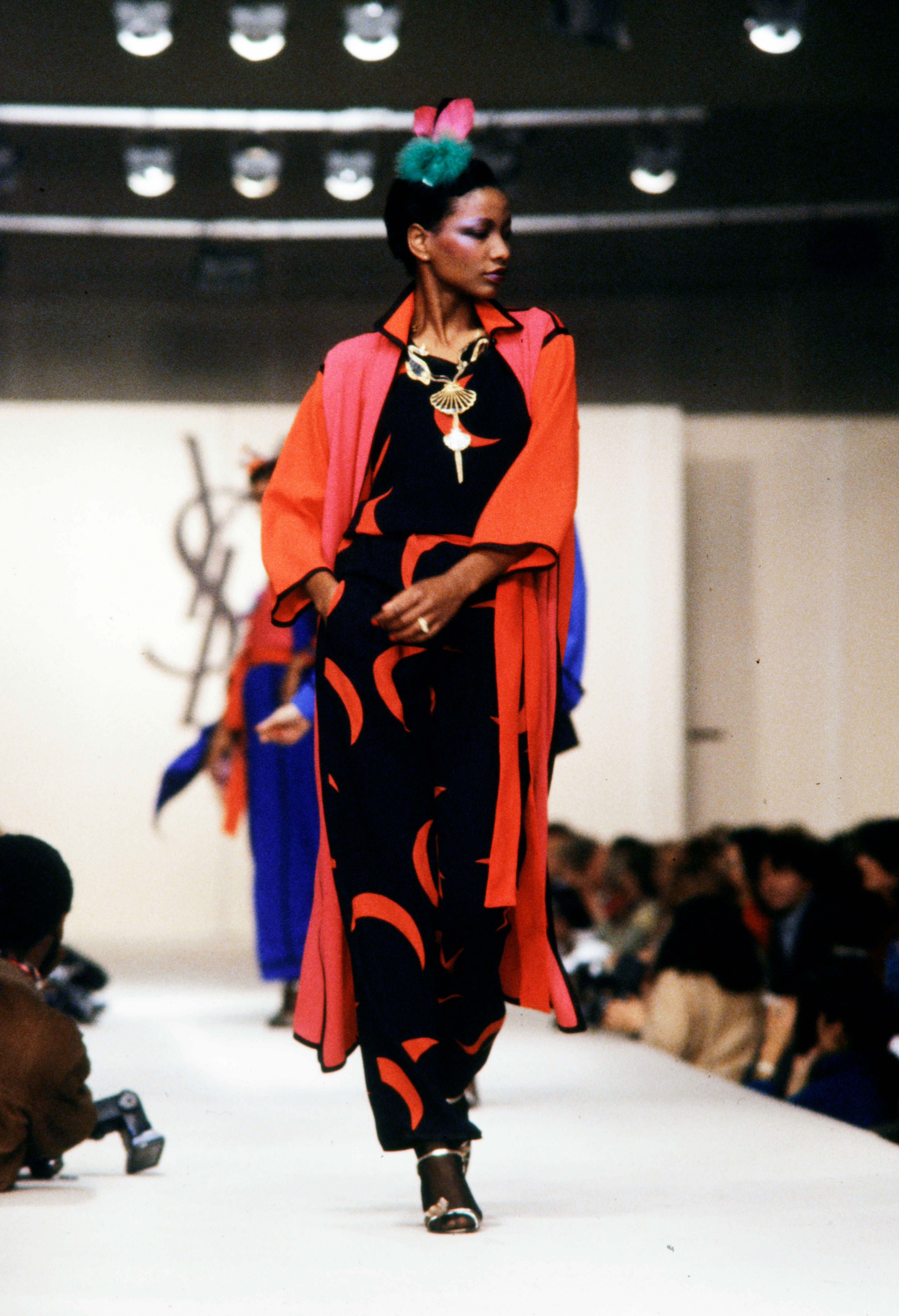 A runway model wears a black and red YSL dress.