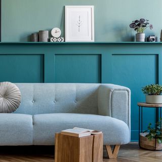 how to panel a wall, blue living room with panelling behind grey sofa, side table, shelf on top of paneling