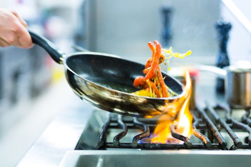 A person cooking with a frying pan.