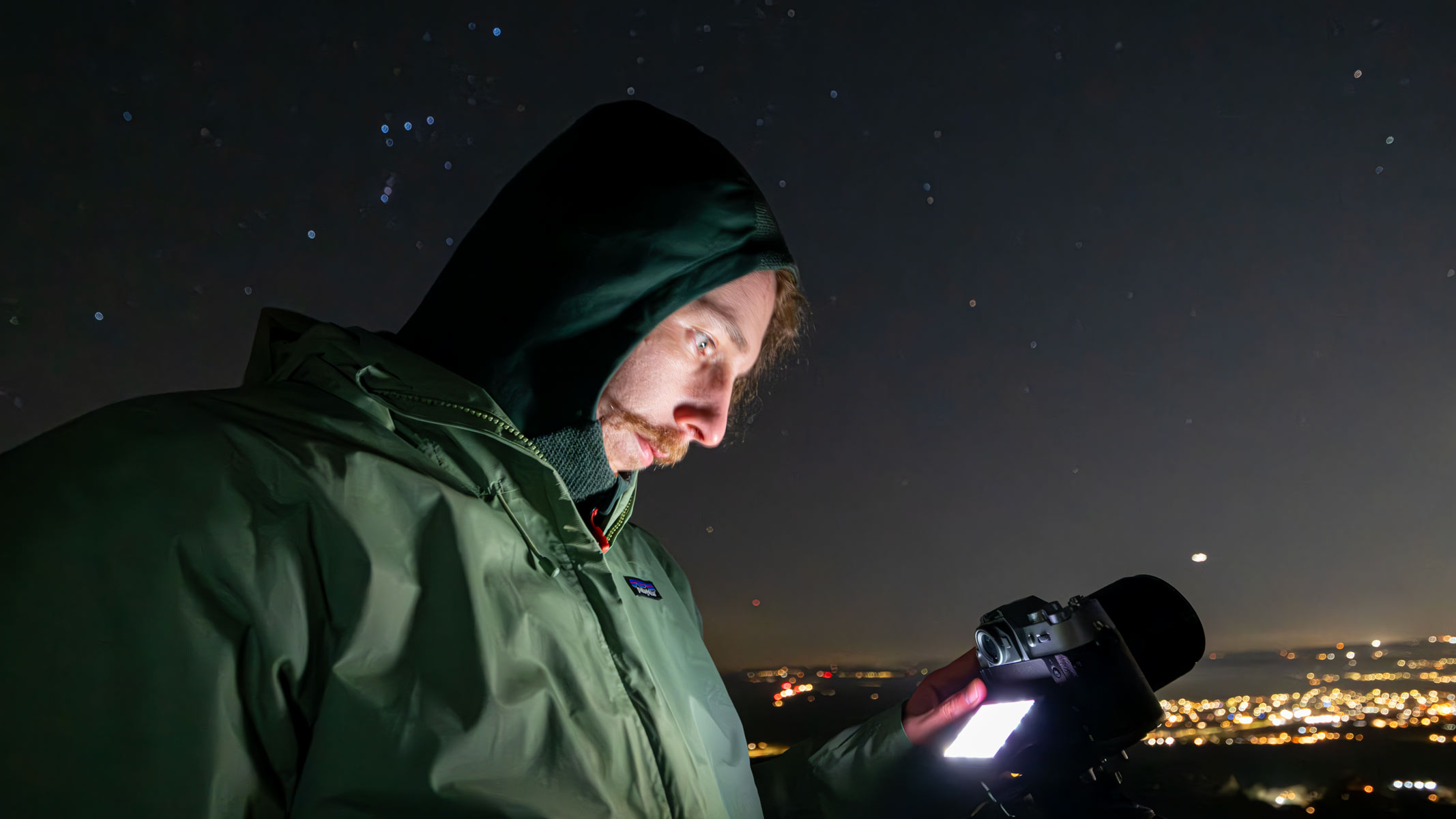 A man looking down at a Fujifilm X-T50 with stars and streetlights in the background