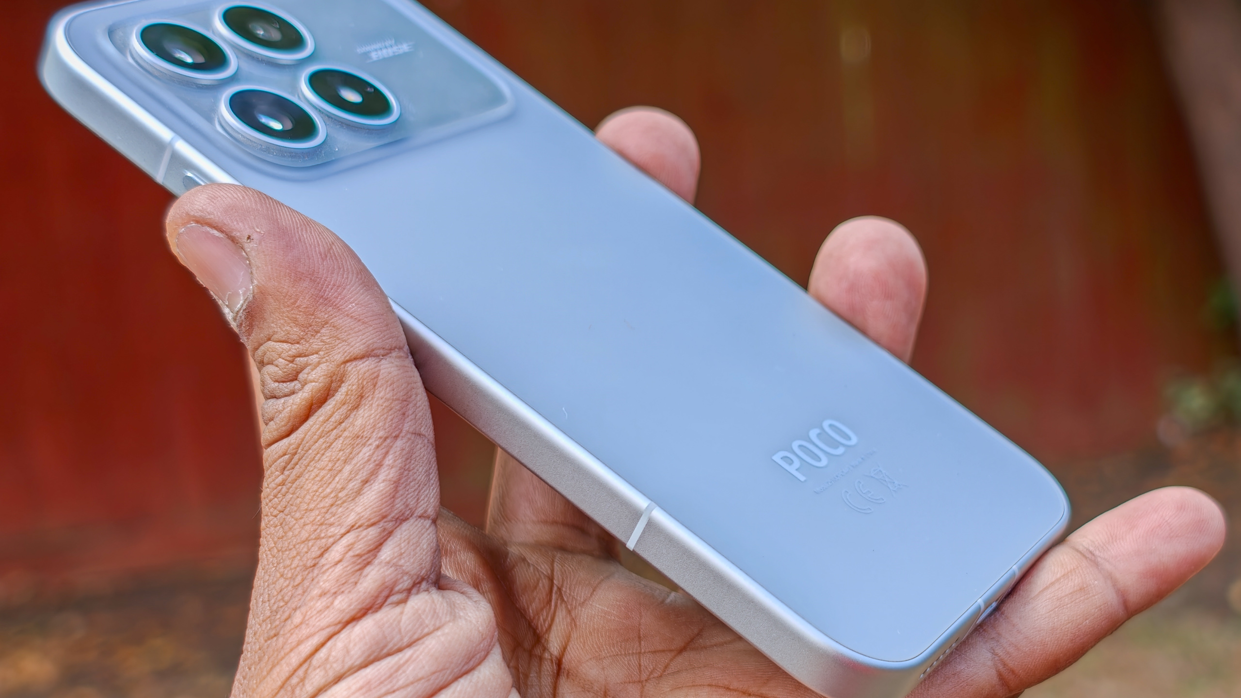 The Poco F8 Pro in Silver in the hand against a garden backdrop