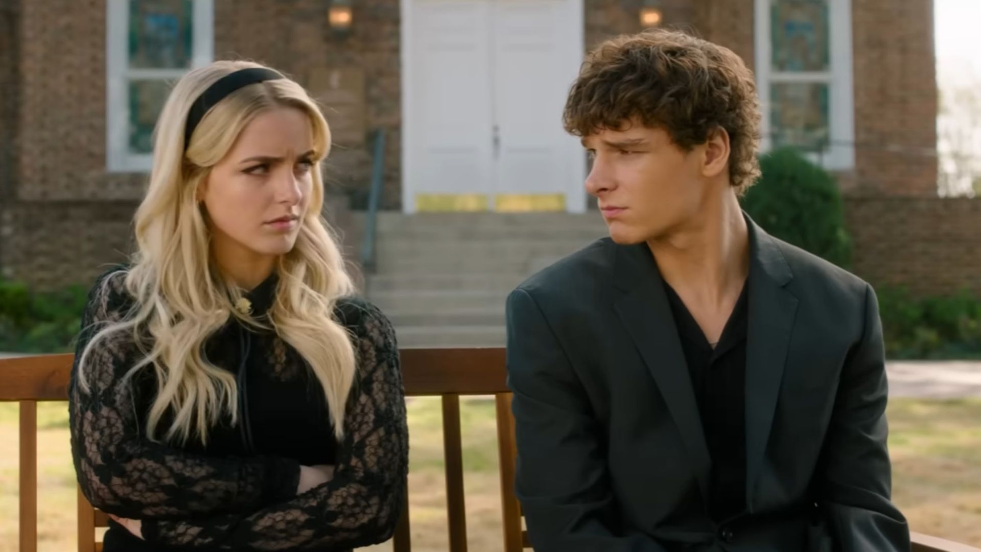 From left to right: Mckenna Grace and Mason Thames sitting on a bench and looking at each other.