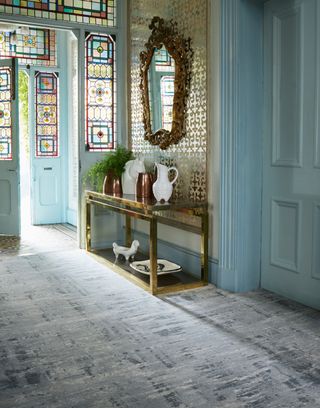 gilded mirror and blue walls in a stately home's hallway with stained glass windows on door and surround