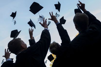 College graduates toss their caps in the air.