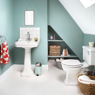 toilet with wash basin and grey wall with commode