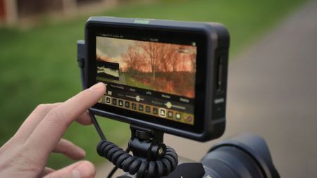 Finger touching the screen of an Atomos Shinobi on-camera monitor