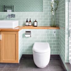 toilet with commode and grey wall tiles