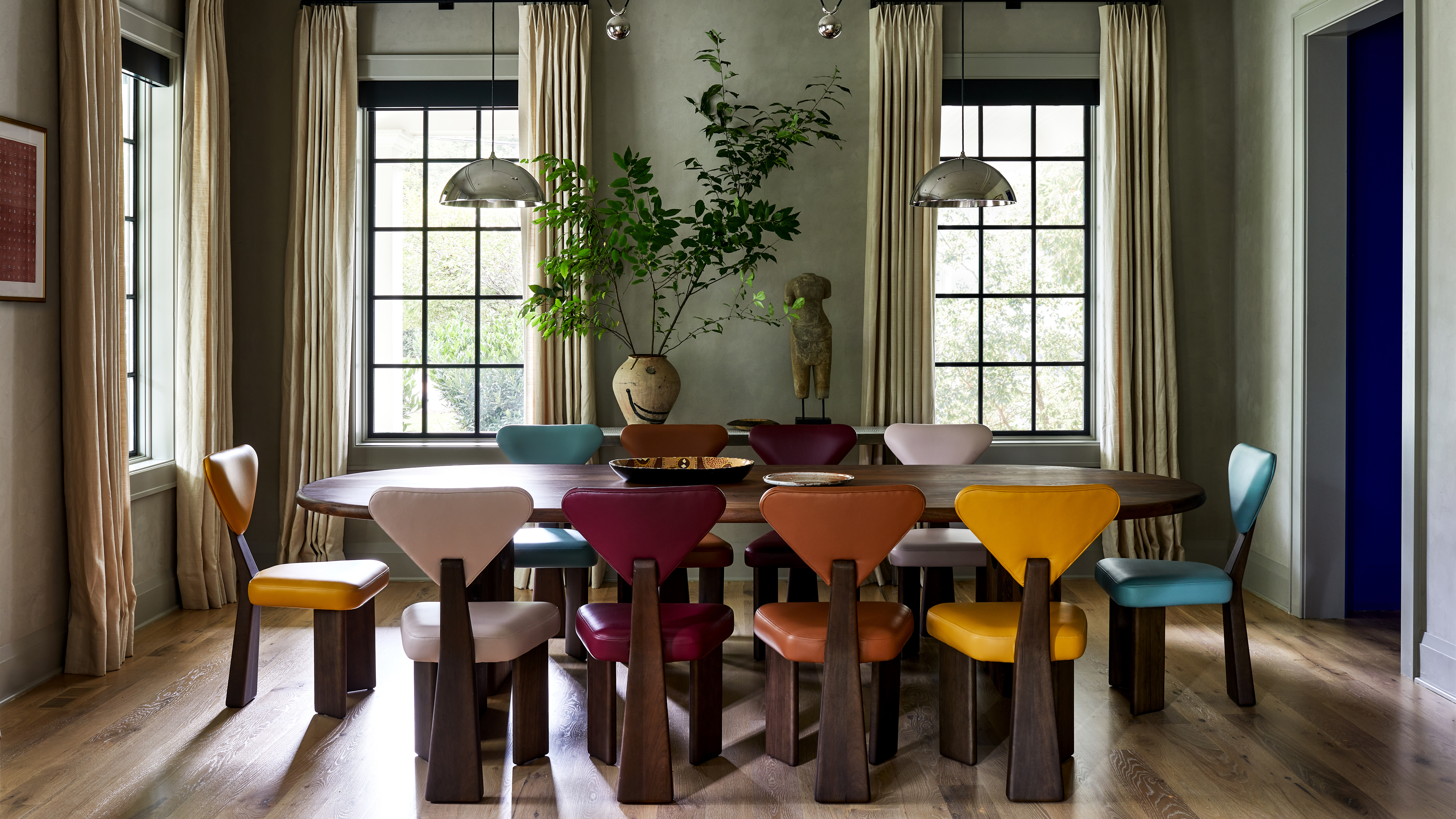 green dining room with multi colored chairs around a wood table