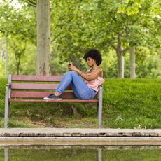 Woman Sitting on Bench Using Phone