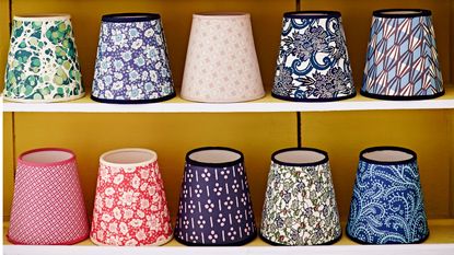 Floral fabric lampshade on blue base next to mug of flowers