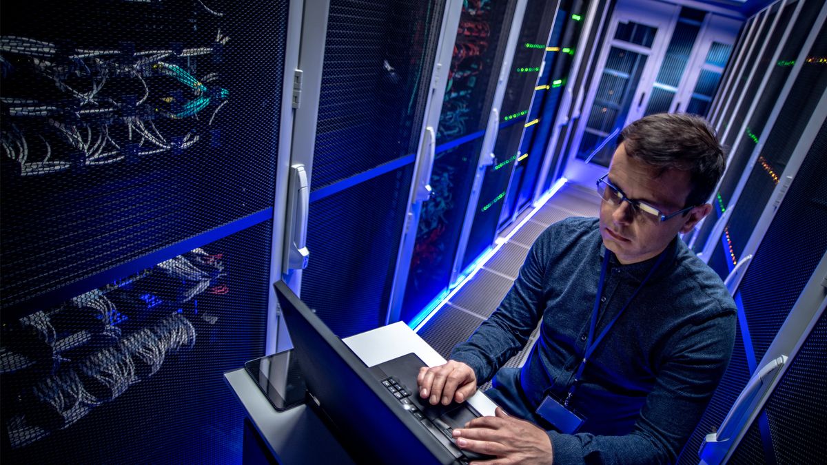 man working on laptop in data centre