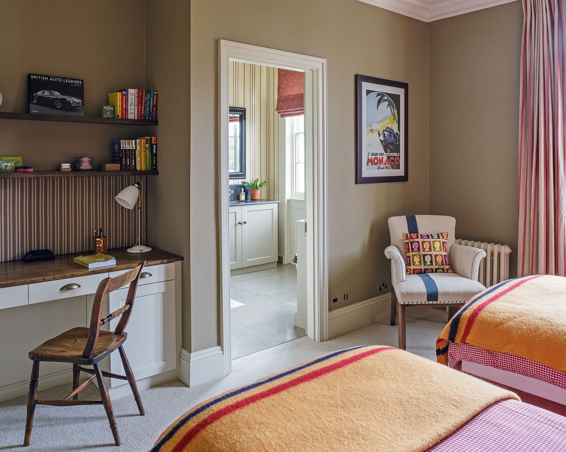A guest room which doubles as an office space with orange throws on the beds