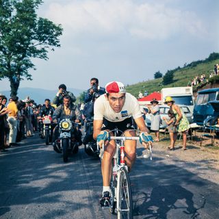 Eddy Merckx rides up a climb flanked by motorbikes and fans